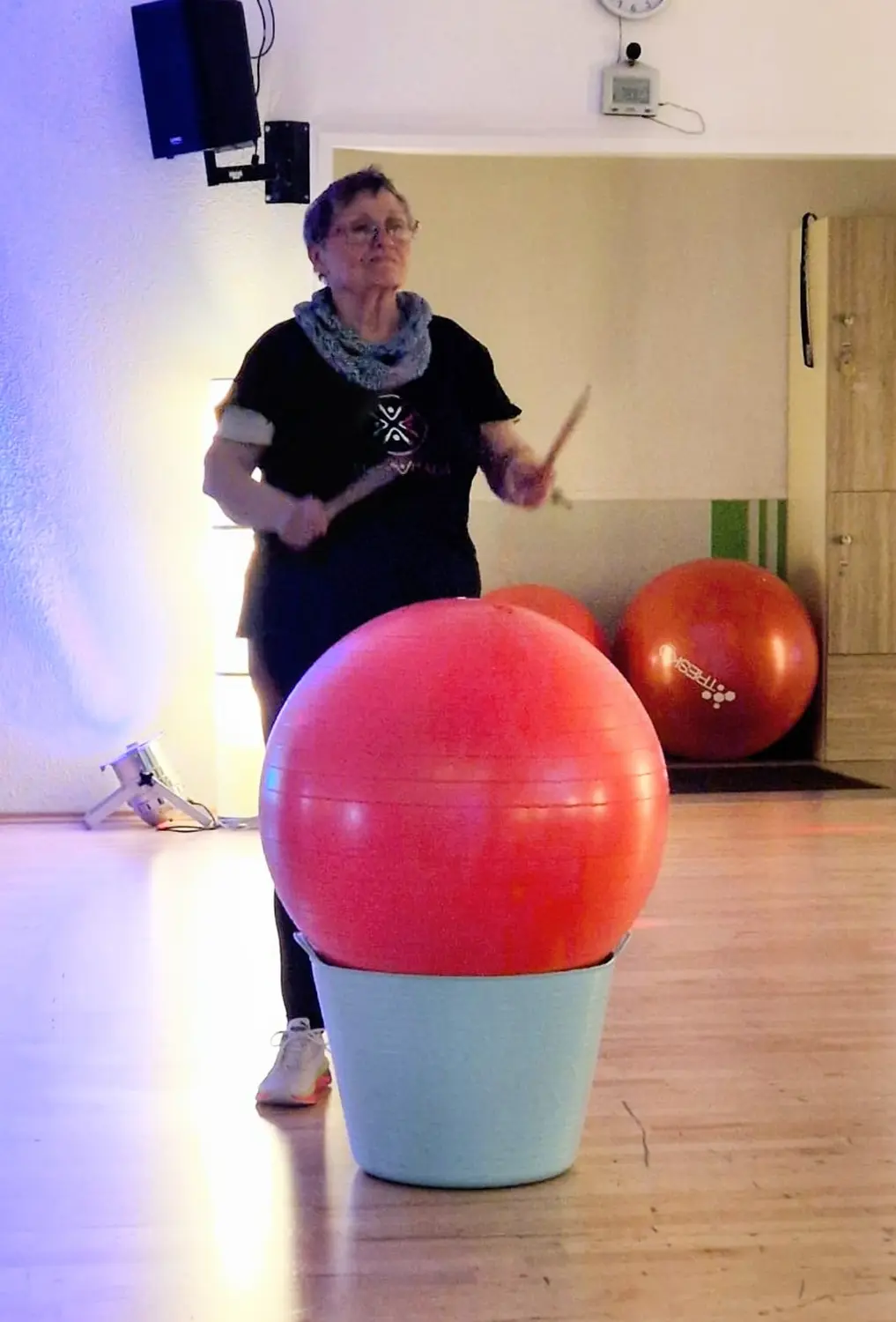 Teilnehmerin beim GOLD-Training mit Trommelstöcken am Gymnastikball