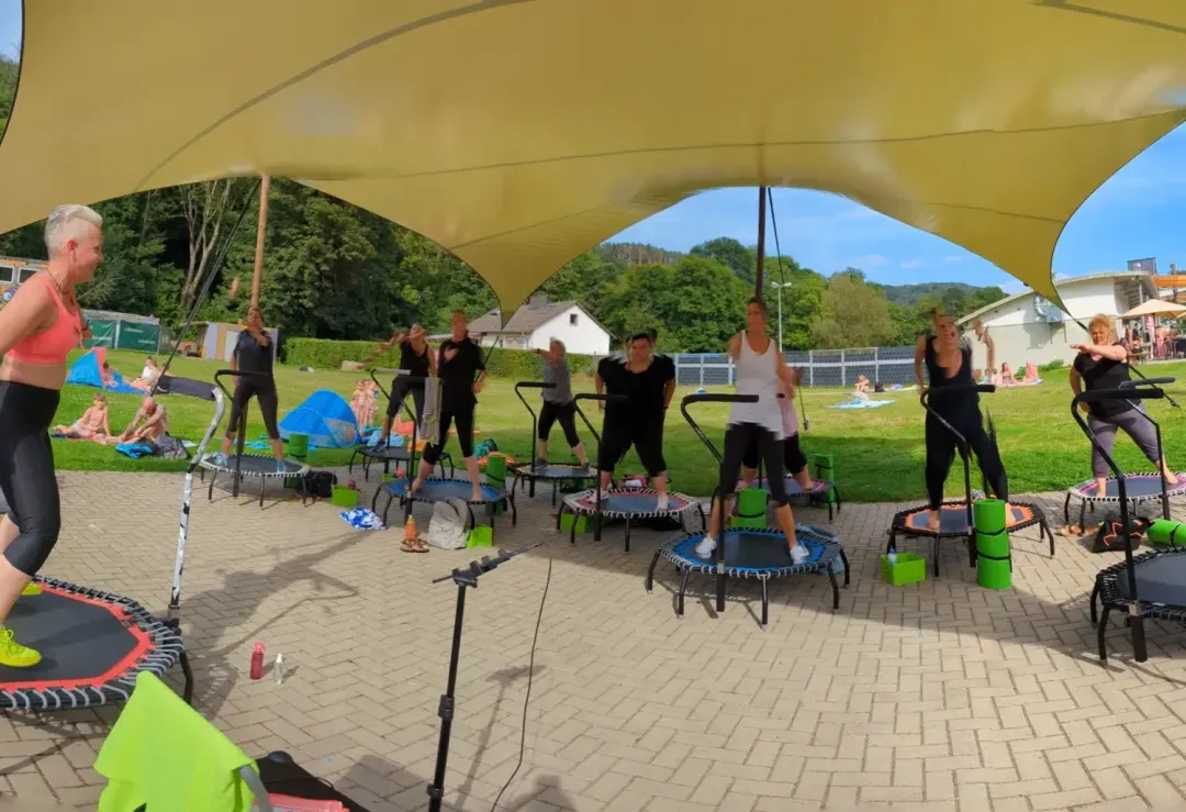 Gruppe beim Trampolintraining unter einem Sonnensegel im Freien