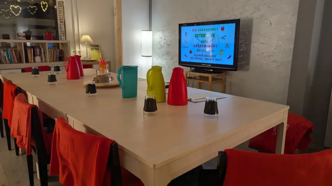 Vorbereiteter Workshop-Raum mit Tischen und Bildschirm